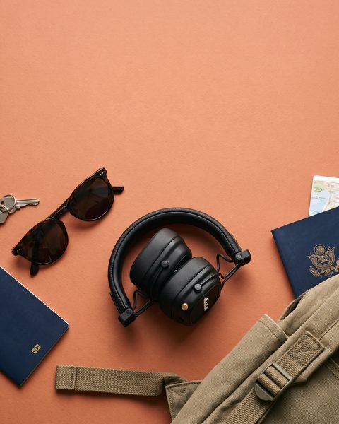 Los auriculares sobre fondo naranja con objetos de viaje
